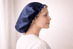 Femme portant le bonnet de nuit en satin Amber bleu nuit avec bordure champagne, vue de profil