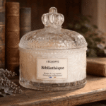 Bougie parfumée Bibliothèque L'Échoppe Buissonnière posée sur une étagère en bois avec des livres anciens et de la lavande