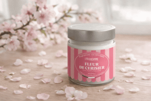 Bougie parfumée Fleur de Cerisier de L'Échoppe Buissonnière avec couvercle posée sur un plan en bois avec des branches et pétales de cerisier