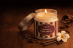 Bougie parfumée Vanille Patchouli de l'Échoppe Buissonnière allumée sur un plan en bois avec une fleur de tiaré, des gousses de vanille et des épices