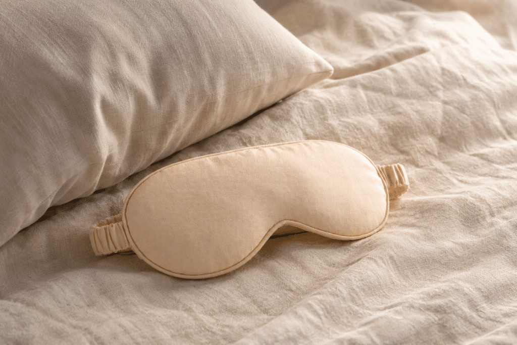 Masque de nuit plat posé près d'un oreiller marqué par le sommeil sur le côté