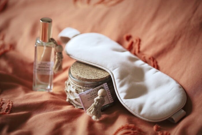 Masque de nuit en bambou posé sur la bougie Instant Zen, à côté de la brume d’oreiller bio